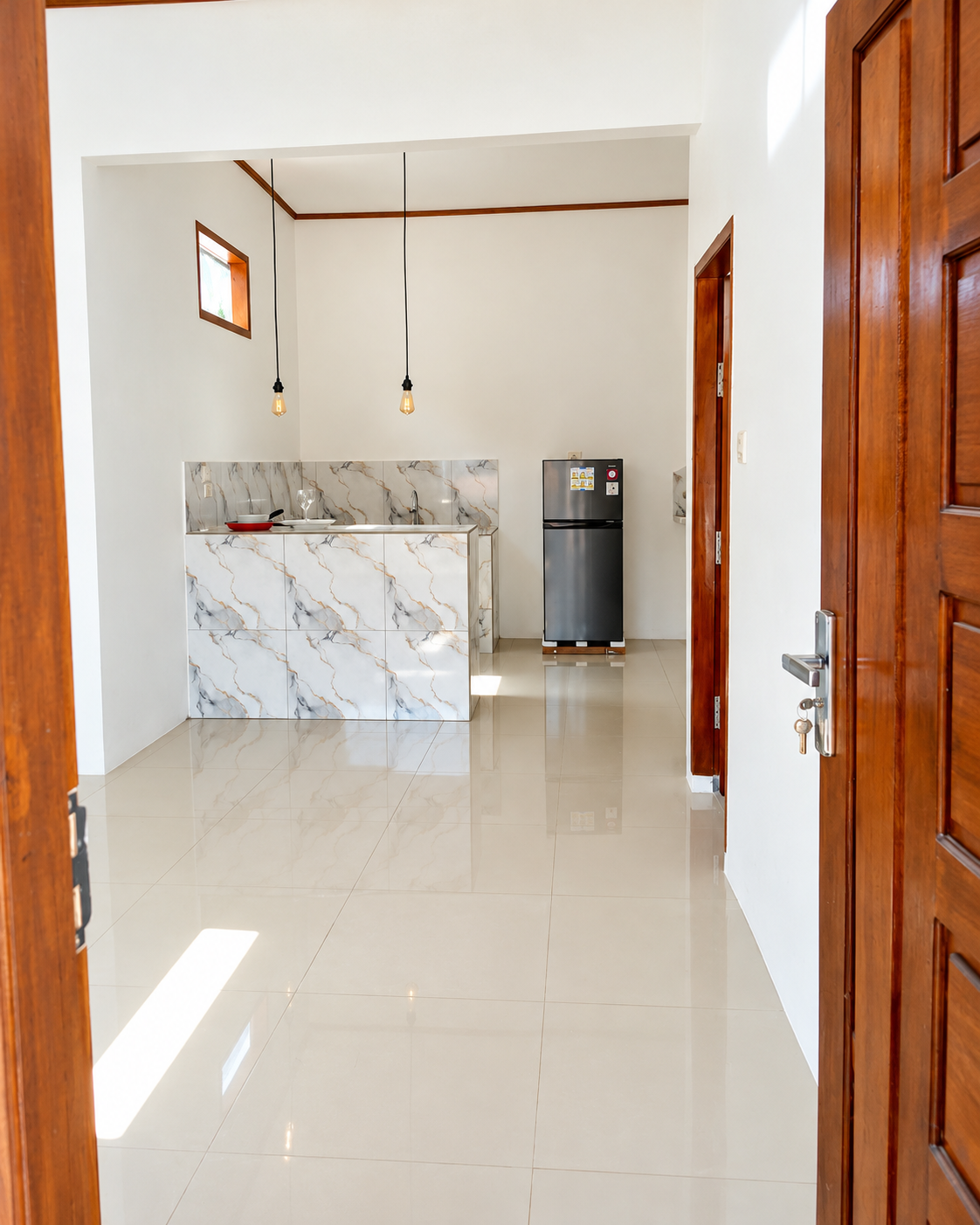 Entrance view into the light-filled living area with tiled floors and kitchen