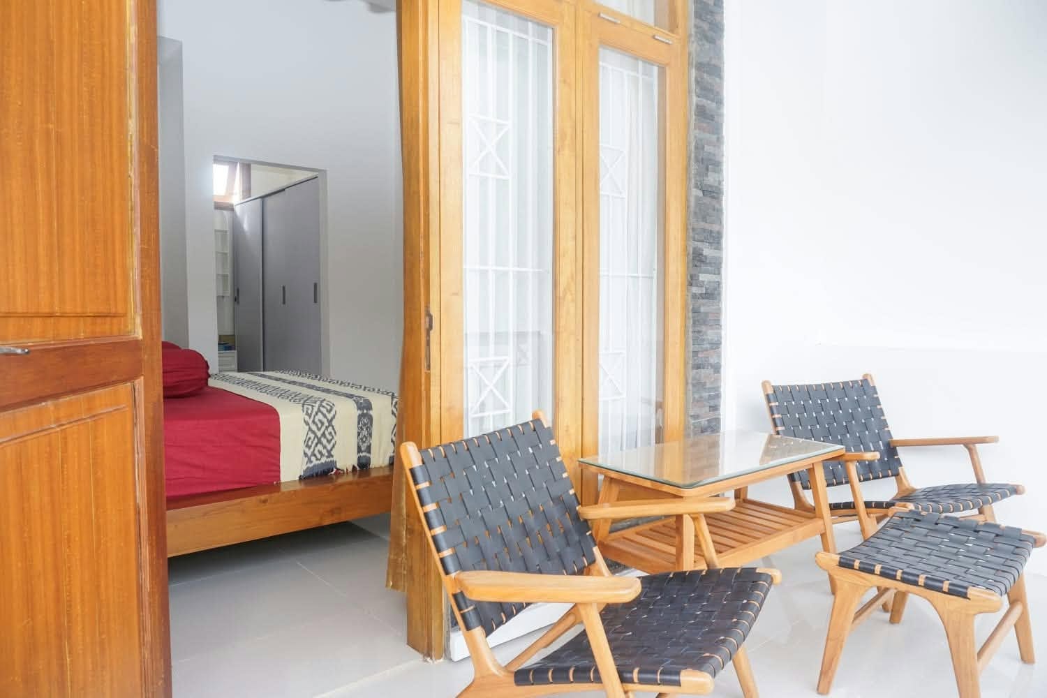 Covered terrace with wooden lounge chairs and double-bedroom doorway