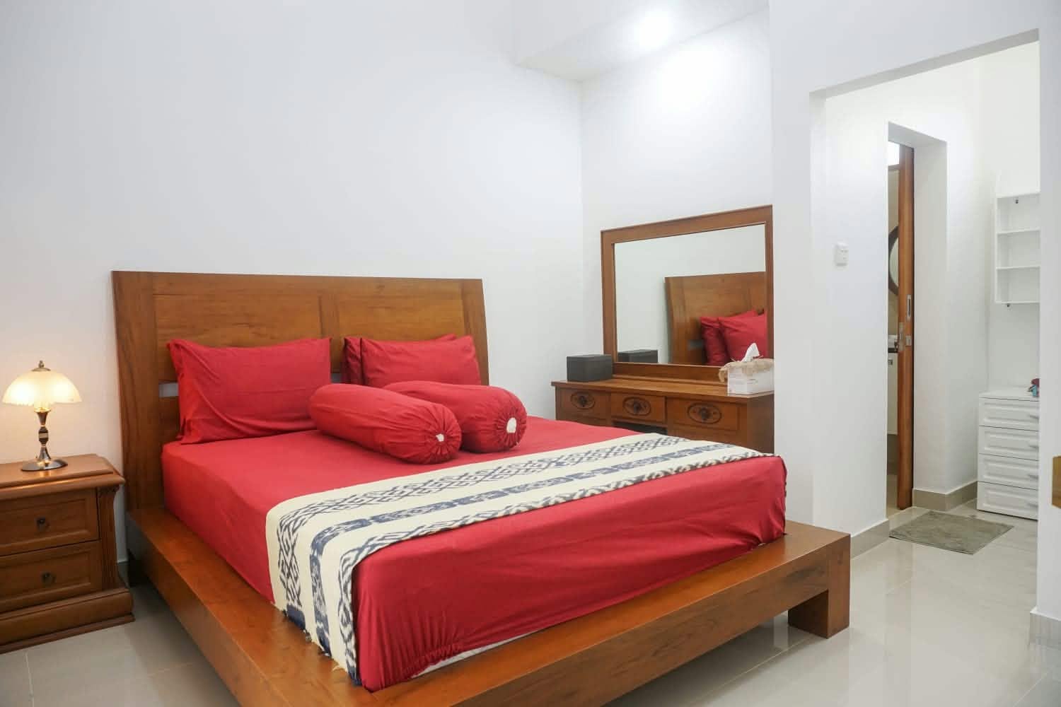 Bedroom with red bed linen and wooden furniture